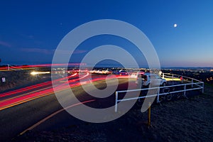 Glowing trails of car lights illuminate parking lot at view point on top of Mount Tolmie