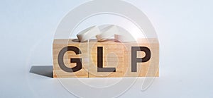 GLP abbreviation stands for Good Laboratory Practice on wood background