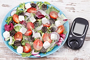 Glucometer for checking sugar level and fresh greek salad. Diabetes and healthy lifestyles