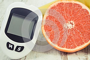 Glucometer for checking sugar level, ripe grapefruit and dumbbells for fitness. Healthy lifestyle and nutrition during diabetes