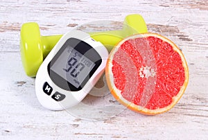 Glucometer, fresh grapefruit and dumbbells for fitness, diabetes, healthy lifestyles