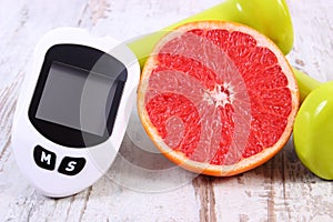 Glucometer for measuring sugar level, fresh grapefruit and dumbbells for fitness, healthy lifestyles concept