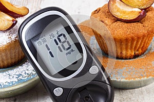 Glucometer, muffins with plums powdered sugar and cinnamon, diabetes and delicious dessert