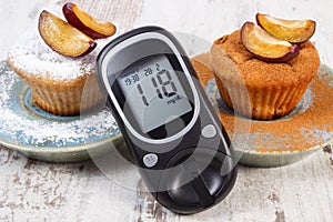 Glucometer, muffins with plums powdered sugar and cinnamon, diabetes and delicious dessert