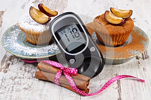 Glucometer, muffins with plums powdered sugar and cinnamon, diabetes and delicious dessert