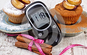 Glucometer, muffins with plums powdered sugar and cinnamon, diabetes and delicious dessert