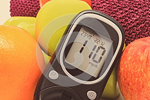 Glucometer with result of sugar level, fresh fruits and dumbbells using in fitness. Healthy nutrition and sporty lifestyles
