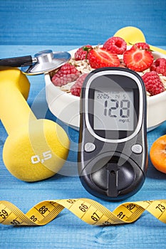 Glucometer with result sugar level, oat flakes with fruits, dumbbells and tape measure, concept of diabetes and healthy lifestyle