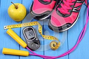 Glucometer, sport shoes, fresh apple and accessories for fitness on blue boards