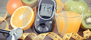 Glucometer with sugar level, fresh fruits and orange juice. Source natural minerals and vitamins