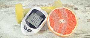 Glucose meter for checking sugar level, ripe grapefruit and dumbbells for fitness. Healthy lifestyle and nutrition during diabetes