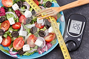 Glucose meter with sugar level, centimeter and greek salad. Diabetes, slimming, healthy lifestyles and nutrition