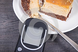 Glucose meter and sweet cheesecake. Measuring and sugar level control during diabetes