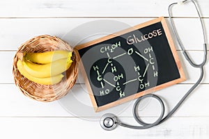 Glucose molecule on blackboard with banana and stethoscope