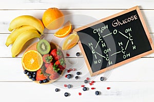 Glucose molecule on blackboard with mixed fresh fruits salad