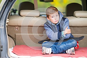Glum little boy sitting in the boot of a car. photo