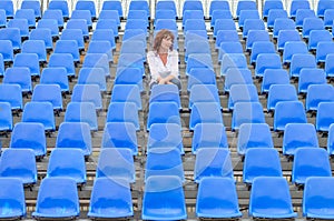 Glum woman sitting in spectator seating photo