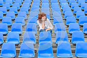 Glum woman sitting in spectator seating photo