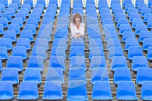 Glum woman sitting in spectator seating photo