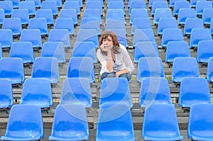 Glum woman sitting in spectator seating photo