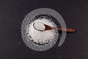 Glutamic acid monosodium salt on dark background. Msg or Food additive E621 in wooden spoon, top view. Selective focus, copy space