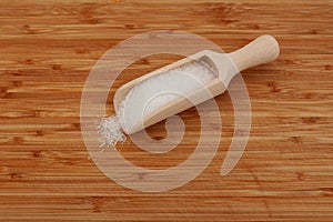 Glutamic acid monosodium salt in wooden scoop on wooden cutting board. Msg. Food additive E621. Flavor seasoning for enhancing