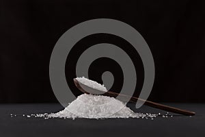 Glutamic acid monosodium salt in a wooden spoon on a dark background. Msg. Food additive E621. Flavor seasoning for enhancing food