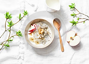 Gluten free breakfast - quinoa, coconut milk, banana, apple, peanut butter bowl on light background, top view. Delicious diet, veg