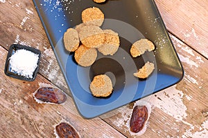 Gluten free cookies with coconut and dates on black plate on wooden background