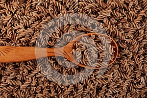 Gluten free flax pasta in wooden spoon. Uncooked Fusilli made of flaxseed flour, close-up. Pasta di Lino. Low glycemic index
