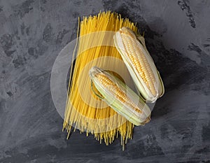 Gluten free pasta from corn  on chalkboard background. Top view.  raw spaghetti, fresh cob of corn