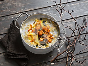 Gluten free pumpkin and apple porridge. Nut milk oatmeal with pumpkin, apples and honey on wooden brown background.