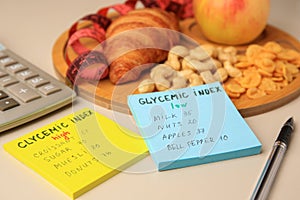 Glycemic index. Notes with information, measuring tape, calculator, pen and products on beige background, closeup