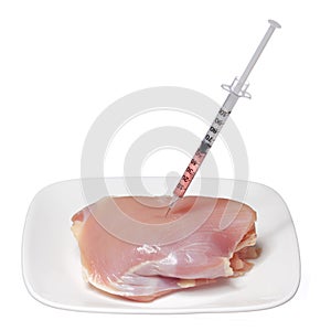 GMO food concept. Genetically modified raw chicken meat on square plate and syringe isolated on white. Genetic injectio