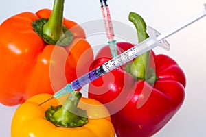 GMO food concept. Syringes are stuck in vegetables with chemical additives. Injections into fruits and vegetables.