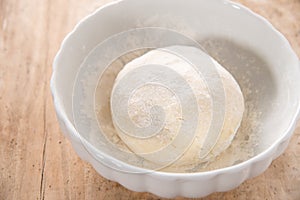 Gnocchi dough in white ceramic bowl on wood