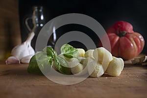 Gnocchi ,italian potato pasta with fresh basil ,garlic ,tomato and olive oil on wood board .Black background