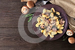 Gnocchi with mushrooms and sage. Overhead table scene on a dark wood background.