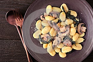 Gnocchi with mushrooms and sage. Top view close up over dark wood.
