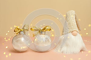 gnome and christmas balls with bokeh on pink - white decorations with feathers. New Year's gifts