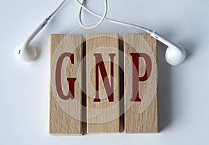 GNP - acronym on wooden blocks on white background with wired headphones