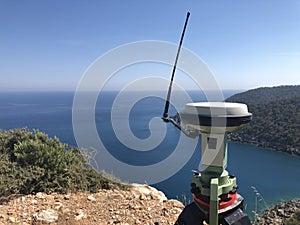 GNSS base receiver stands on the tripod at the hill top against sea at the background photo