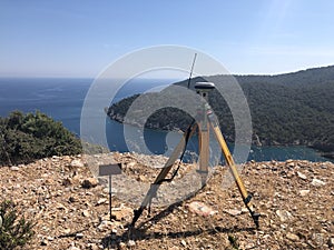 GNSS base receiver stands on the tripod at the hill top against sea at the background photo