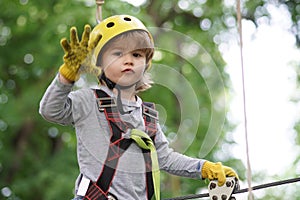 Go Ape Adventure. Hiking in the rope park girl in safety equipment. Little child climbing in adventure activity park