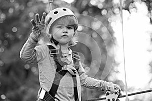 Go Ape Adventure. Hiking in the rope park girl in safety equipment. Little child climbing in adventure activity park