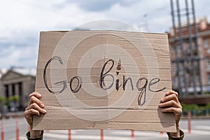 Go binge. cheeky rebellious Text in a sign. Hand holding banner photo