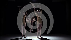 Go on contemporary dance of three girls in white dresses, on black, shadow, slow motion