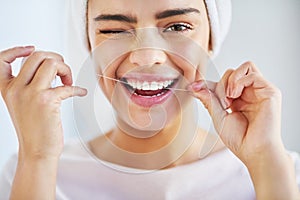 Go the extra mile for your smile. Portrait of a beautiful young woman flossing her teeth in the bathroom at home.