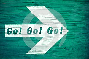 Go! Go! Go! ahead motivational goal text written on white directional arrow pointing towards right painted green wood