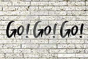 â€œGo! Go! Go!â€ motivational text written on a white stone brick wall background